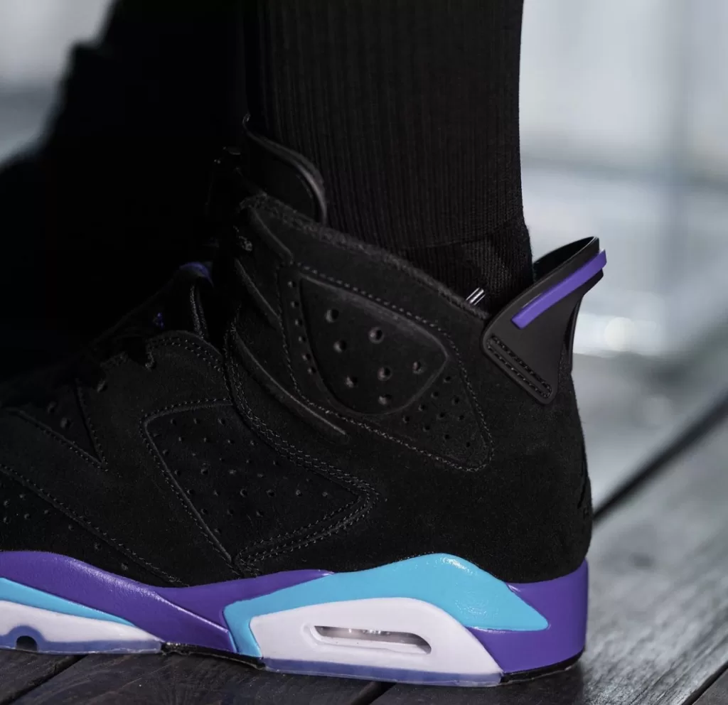 Image displaying the Air Jordan 6 "Aqua" sneakers in a Black, Bright Concord, and Aquatone color scheme, featuring a sleek design with a Black nubuck upper and contrasting accents, resting on an icy translucent outsole.