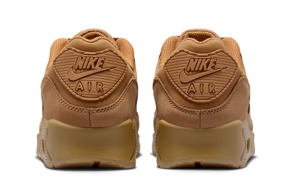 A pair of Nike Air Max 90 sneakers in "Wheat" colorway. The shoes feature a suede and nubuck upper with matching Swooshes, laces, and branding elements. The sole unit is also brown, with a visible Air unit and semi-translucent outsole.